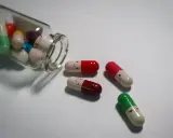 Kolorowe kapsułki z uśmiechniętymi buźkami, niektóre wypadły z buteleczki. Tak działają leki na depresję, przynosząc ulgę.