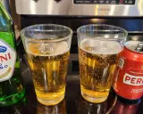 Dwa szklanki orzeźwiającego peroni piwo, obok zielona butelka i czerwona puszka. Idealne na włoskie popołudnie.