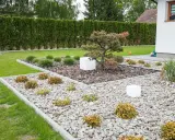 Nowoczesne klomby w ogrodzie galeria: kamień, kora, trawy ozdobne i miniaturowa sosna tworzą minimalistyczną kompozycję.