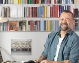 Fabio Volo sorride tra gli scaffali pieni di libri, forse in attesa di presentare il suo ultimo libro.