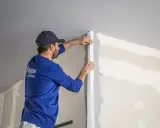 Fachowiec montuje narożnik przy klejeniu płyt GK na ściany.
