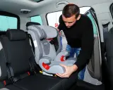 Mężczyzna montuje fotelik dziecięcy, pokazując, jak zamontować isofix w aucie.