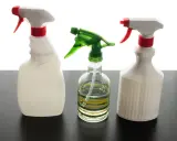 Trois flacons pulvérisateurs, dont un transparent avec des rayures vertes et jaunes, suggèrent un désinfectant naturel pour un nettoyage écologique.