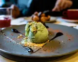 Pyszne lody pistacjowe na talerzu, ozdobione czekoladą i posypką. Idealny deser na poprawę humoru.