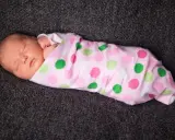 Schlafendes Baby, in rosa gepunktete Decke gewickelt. Pucken ja oder nein? Die süße Kleine scheint es zu mögen.