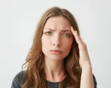 Donna con mano sulla tempia, espressione preoccupata, forse per lo stress ossidativo della pelle.