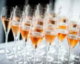 Reihe von Champagnergläsern mit Rosé-Champagner, bereit für den Genuss. So trinkt man Champagner: mit Stil und Freude.