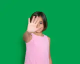 Niña de 4-5 años muestra timidez en niños, cubriendo su rostro con la mano.