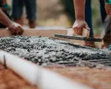 Dłoń wyrównująca świeży beton kielnią na budowie.