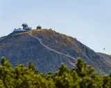 Szczyt Śnieżki w Karkonoszach, z obserwatorium i schroniskiem, po którym wije się ścieżka turystów. W tle kolejka linowa.