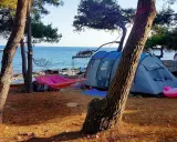 Idealne wakacje: chorwacja pod namiotem, z hamakiem, dmuchanym flamingiem i widokiem na morze.