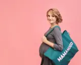 Przyszła mama z torbą "Mamahood" zastanawia się, kiedy spakować torbę do szpitala.