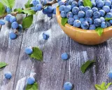 Frische Schlehen in einer Holzschale und auf rustikalem Holztisch, bereit für leckere Schlehen Rezepte.