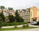 Sanatorium Rafał Busko Zdrój, z żółtą fasadą i zielenią wokół, zaprasza na wypoczynek.