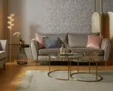 Przytulny salon glamour z beżową kanapą, różowymi poduszkami i złotymi dodatkami.