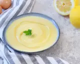 Cremige Joghurt-Mayonnaise mit Zitrone und Petersilie, daneben Eier und Zitronen.