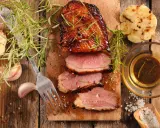 Magret de canard tranché, servi avec une sauce pour magret de canard, romarin, ail rôti et gros sel.