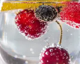 Erfrischendes Getränk mit Kirschen, Blaubeeren und Zitrone in sprudelndem Wasser. Der Unterschied Sodawasser und Mineralwasser liegt in der Kohlensäure.