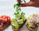 Tres tostadas gourmet: tomate, pepino y aguacate con rábano. La mejor variedad de aceite de oliva para tostadas realza sus sabores.