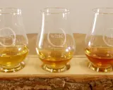Fünf Gläser mit unterschiedlichen Farben von **whiskey ohne farbstoff** stehen auf einem Holzbrett.