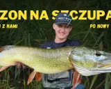 Szczęśliwy wędkarz trzyma ogromnego szczupaka, idealny okaz, kiedy żeruje szczupak. Sezon na szczupaki trwa!