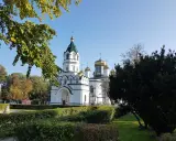 Biała cerkiew ze złotymi kopułami, otoczona zielenią. Piękny widok na szlak tatarski w słoneczny dzień.