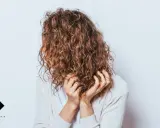 Frauen mit einer voluminösen Dauerwelle, die ihre Hände durch die Locken gleiten lassen.