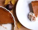 La tarta de calabaza de la abuela, con su relleno cremoso y corteza dorada, lista para ser disfrutada. Una rebanada servida con nata montada y canela.
