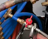 Réglage de la vanne arrivée d'eau maison avec une clé. Tuyaux bleus et rouges, raccords en laiton.