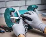 Manos enguantadas afilando tijeras de podar en una amoladora, chispas vuelan.