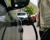 Persona che collega il cavo di ricarica a un'auto elettrica, pensando alle tariffe ricarica auto elettrica.