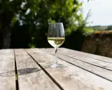 Verre de vin blanc pétillant, un cépage bourgogne aligoté, sur une table en bois à l'extérieur.