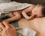 Ein Neugeborenes schläft auf der Brust seines Vaters. Die Frage "wie werde ich ein guter vater" wird hier durch diese liebevolle Szene beantwortet.