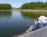 Osoba łowi ryby nad jeziorem Tuchlin, ciesząc się spokojem i pięknem natury.