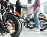 Dwóch mężczyzn ściska sobie dłonie przy motocyklach. Sfinalizowali sprzedaż motocykla przed upływem 6 miesięcy.