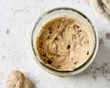 Ein Glas mit Sauerteig, angesetzt mit Roggenvollkornmehl, zeigt Bläschen und eine lebendige Textur.