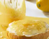 Ein Brötchen mit cremigem Lemon Curd, das ist die Antwort auf die Frage: was ist Lemon Curd. Daneben ein Glas voller dieser gelben Köstlichkeit.