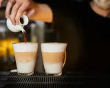 Barista wlewa espresso do dwóch latte macchiato. Zastanawiasz się, ile kcal ma latte macchiato?
