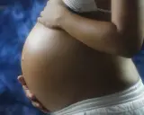 Pancia di donna incinta, con mani che la accarezzano. Si intravede un bikini bianco e uno sfondo blu. L'addome è tonico, forse con un leggero intestino iperecogeno visibile.