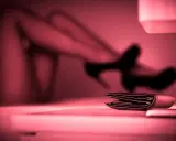Portfel na stole, w tle niewyraźne nogi w szpilkach. To może być symbol tego, czym jest sexworking.