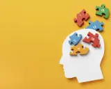 Biały profil głowy z kolorowymi puzzlami z cyframi wpadającymi do środka.