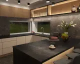Nowoczesna kuchnia z wyspą, na której stoi ciasto i filiżanka kawy. Nad blatem kuchennym wiszą eleganckie lampy.