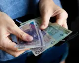 Ręce liczą banknoty, zastanawiając się, ile lat pracy do emerytury.