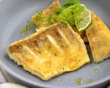 Zanderfilet ohne Haut braten: goldbraune Fischfilets auf grauem Teller, garniert mit Dill und Limettenspalten.