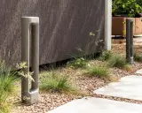 Deux bornes d'éclairage modernes en béton, bordant un chemin. L'ensemble respecte la norme éclairage lux pour un jardin contemporain.