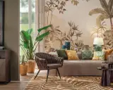 Un salotto con un murale botanico, mobili eleganti e raffinate decorazioni. Un divano beige, una poltrona marrone e un tappeto animalier creano un'atmosfera accogliente.