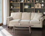 En bekväm soffa framför en bokhylla som ger inspiration. En ljus och inbjudande sittgrupp med en träbricka och doftpinnar.