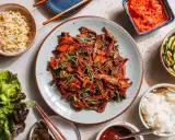 Ein köstliches koreanisches BBQ-Rezept mit gebratenem Fleisch, Beilagen wie Kimchi, Gurkensalat, Sprossen und Reis.
