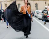 Donna con gonna nera plissettata e giacca in pelle marrone, un look audace che esprime la sua lybido abbigliamento.