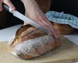 Krojony bochenek chleba z długim terminem ważności, z chrupiącą skórką, na desce do krojenia.